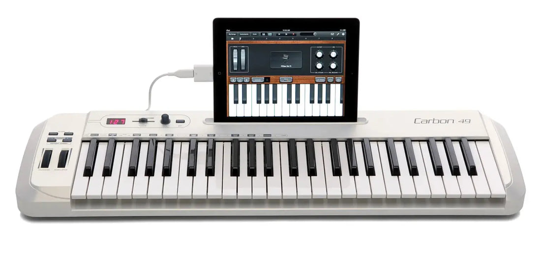 Samson Carbon 49 MIDI controller connected to laptop and iPad in a home studio setup.