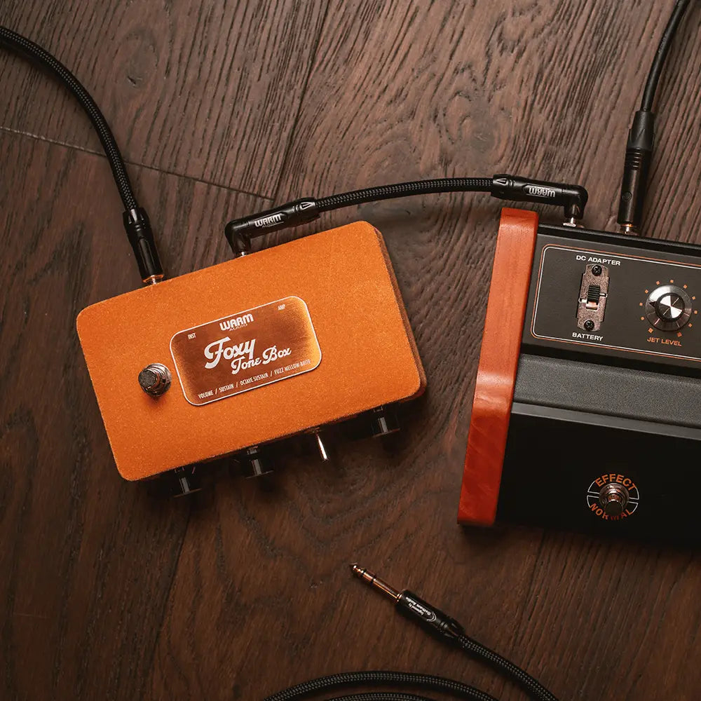 Orange and black guitar effects pedals on a wooden surface
