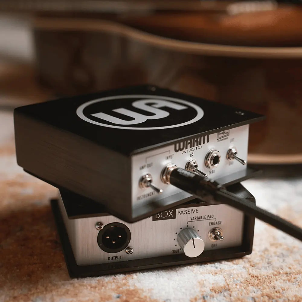 Warm Audio passive DI box with a guitar in the background